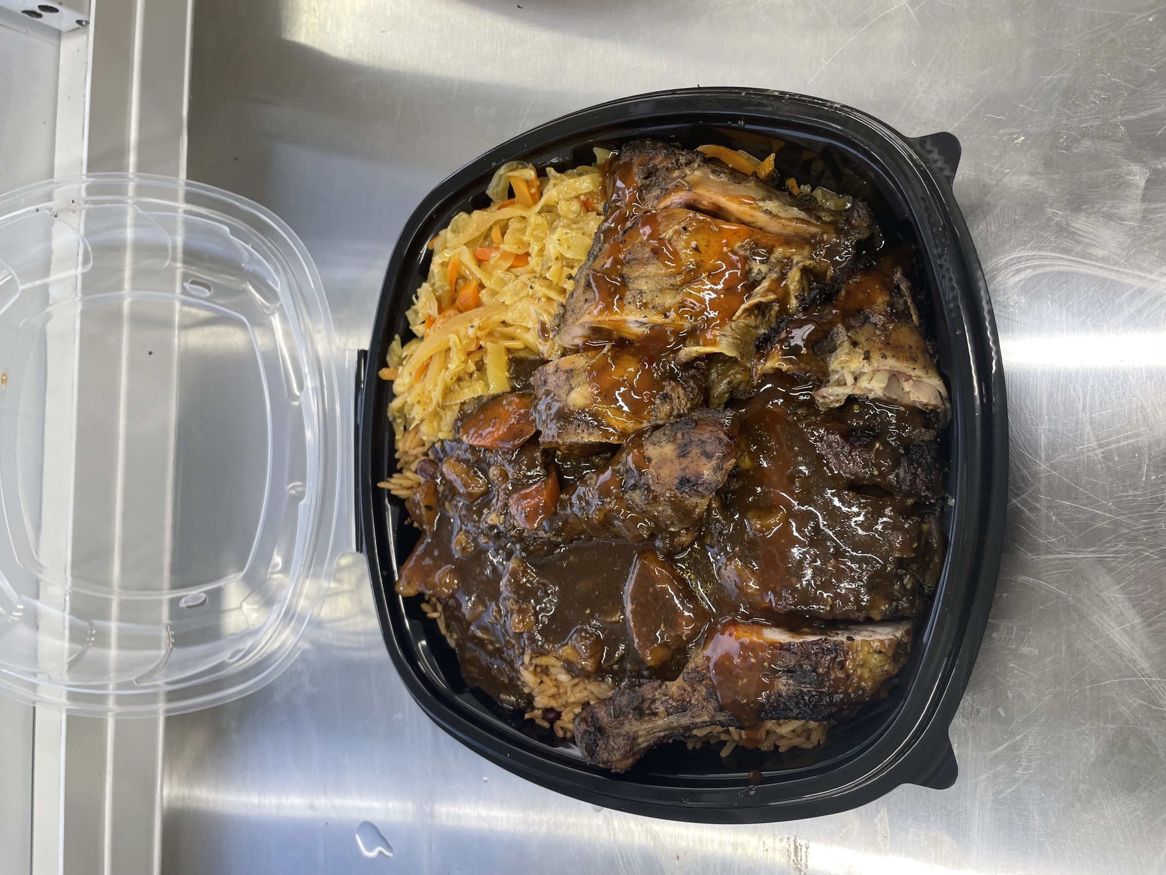 Jamaican Smokehouse jerk chicken and ribs plate with rice and peas and cabbage